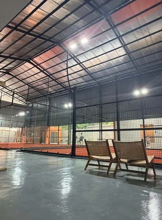 Rattan chairs beside the courts at Filari Padel